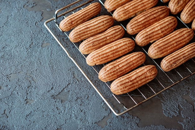 Eclair di dessert di pasticceria francese. Le torte alla crema aromatica appena sfornate si raffreddano su una griglia. Messa a fuoco selettiva morbida.