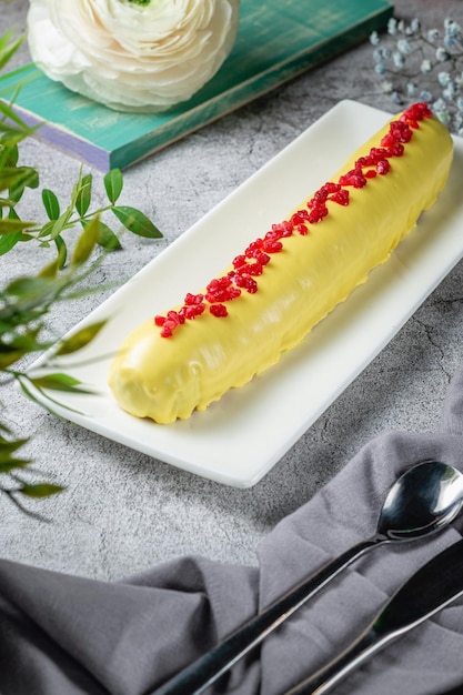 Eclair lunghi fatti in casa in glassa di banana decorati con lamponi su un tavolo di pietra grigia. Menù Ristorante