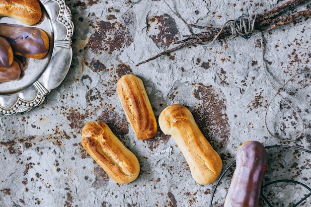 Eclairs fatti in casa in glassa colorata su uno sfondo di cemento in metallo