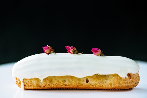 Eclairs o profiteroles con glassa di cioccolato bianco al gusto di rosa su sfondo bianco e nero