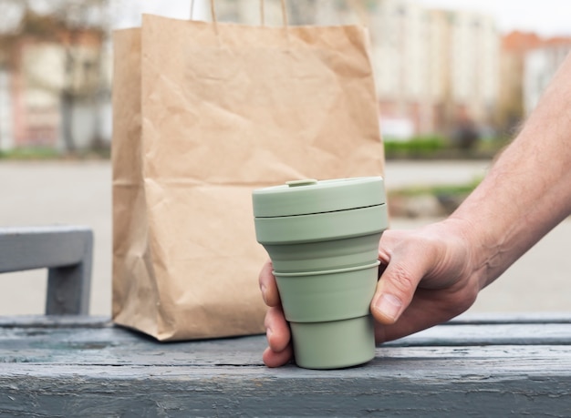 Eco tazza pieghevole in silicone per caffè da asporto. Mano maschile con tazza sostenibile.