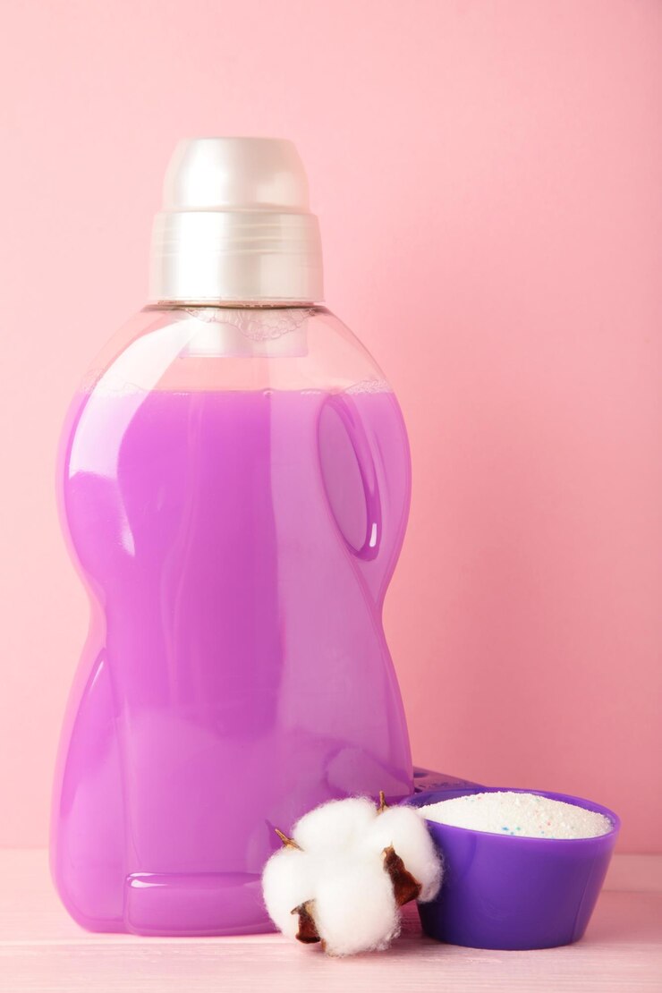 Eco washing concept Laundry detergent with cotton flowers on pink background copy space Vertical photo