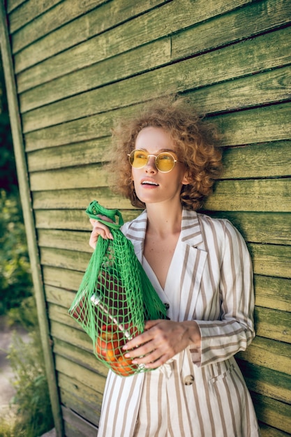 Ecologico. Immagine di una giovane donna in occhiali da sole con una borsa a rete