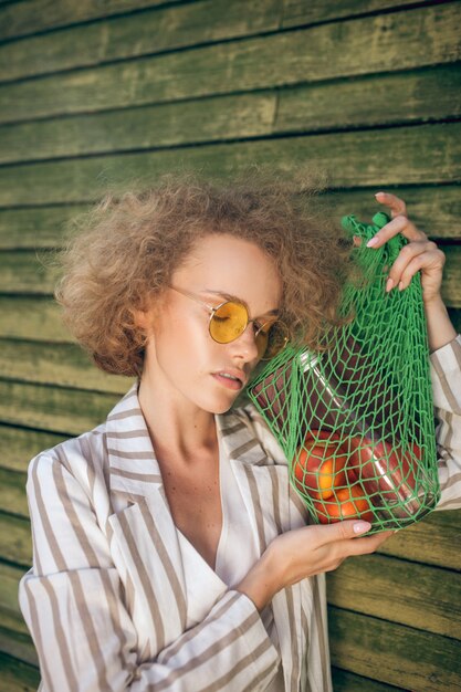 Ecologico. Immagine di una giovane donna in occhiali da sole con una borsa a rete