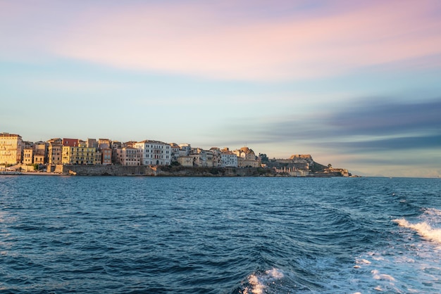 Edifici dell'isola di Corfù sulla riva e sull'acqua di mare al tramonto