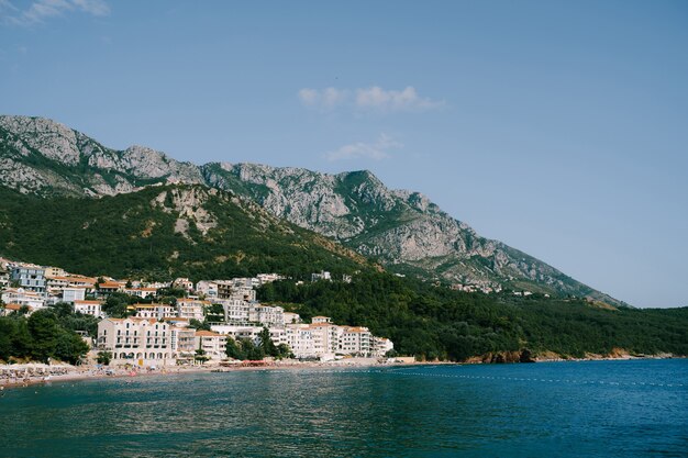 Edifici e hotel sulla costa montenegrina sullo sfondo delle montagne rocciose del villaggio