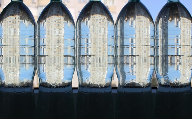 Edifici residenziali riflessi in bottiglie di plastica riempite con acqua limpida