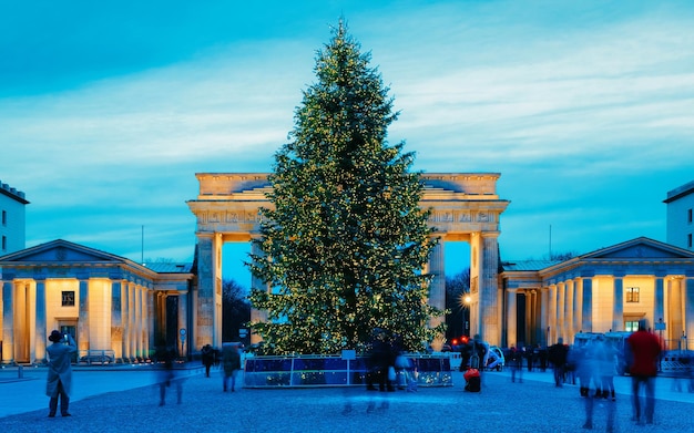 Edificio della Porta di Brandeburgo di Berlino, Germania. Illuminato di notte. Albero di Natale in strada in inverno. Storia e turismo per persone, viaggiatori e turisti. Cielo azzurro di sera