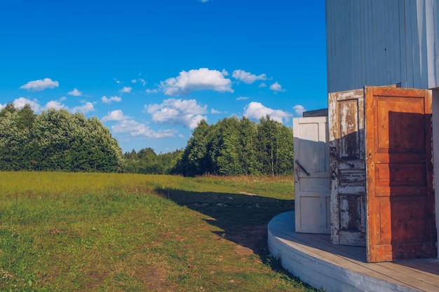 Edificio in legno bianco con molte porte con vista su un campo di erba verde prato