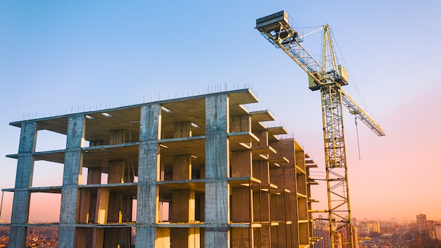 Edificio multipiano, gru a torre e cantiere, vista dall'alto. Al tramonto.