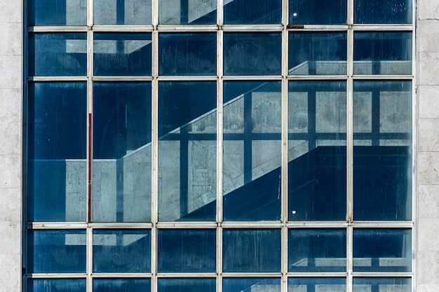 Edificio per uffici ad alta tecnologia con pareti trasparenti che riflettono un cielo azzurro con nuvole. Architettura moderna. Sfondo di vetro astratto