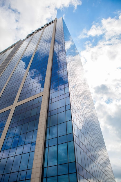 Edificio per uffici moderno di vetro affumicato contro un cielo nuvoloso blu