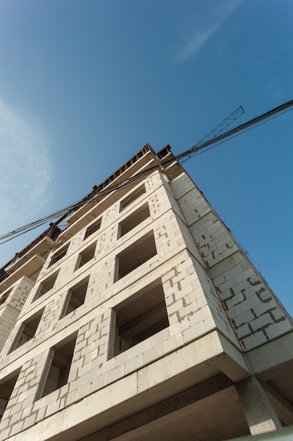 Edificio residenziale multipiano in costruzione e gru su uno sfondo di cielo blu