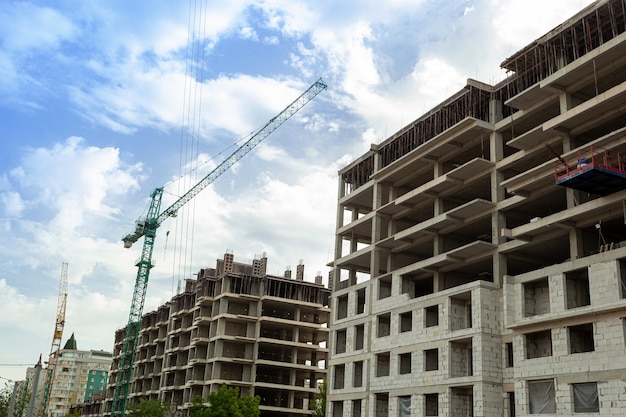 Edificio residenziale multipiano in costruzione e gru su uno sfondo di cielo blu