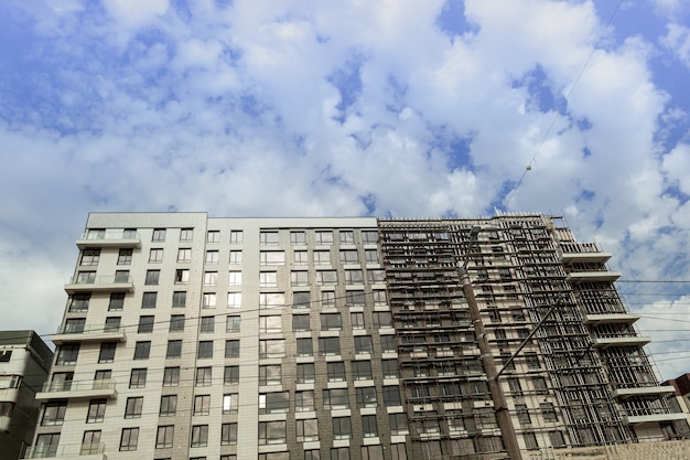 Edificio residenziale multipiano in costruzione e gru su uno sfondo di cielo blu