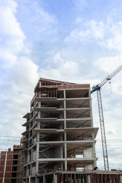 Edificio residenziale multipiano in costruzione e gru su uno sfondo di cielo blu