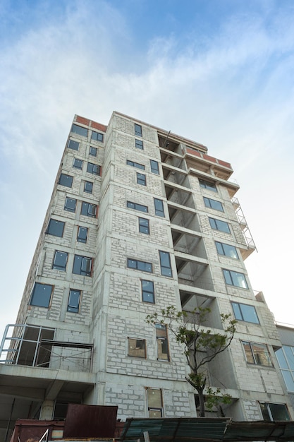 Edificio residenziale multipiano in costruzione e gru su uno sfondo di cielo blu