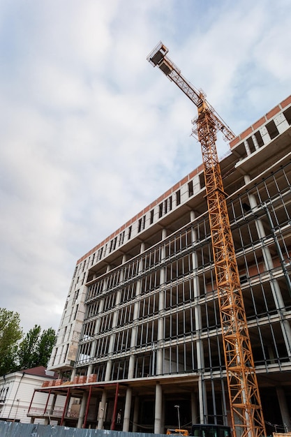 Edificio residenziale multipiano in costruzione e gru su uno sfondo di cielo blu