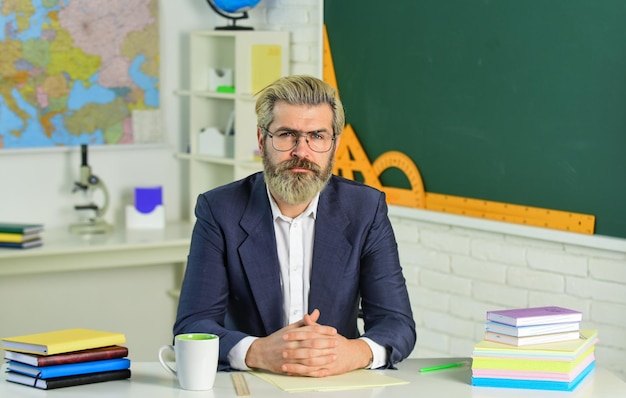 Educatore intelligente maturo bello hipster Dopo le lezioni Certificato di laurea Documenti documenti documenti Compiti a scuola Ritorno a scuola Giornata della conoscenza Uomo lavoro insegnante di scuola seduto in classe