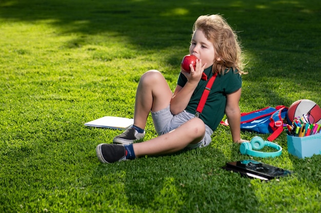 Educazione all'aperto del bambino Bambino che fa i compiti all'aperto e che mangia mela