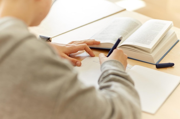 educazione, apprendimento e concetto di persone - primo piano del ragazzo studente con taccuino e test scolastico di scrittura del libro