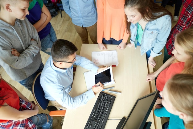 educazione, apprendimento, insegnamento, tecnologia e concetto di persone - gruppo di studenti e insegnante con computer tablet pc a scuola