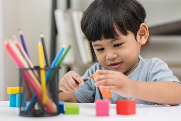 Educazione asiatica del ragazzino da casa Sviluppare l'apprendimento dei bambini prima di entrare nella scuola materna Pratica le abilità di giocare con i giocattoli di legno nel soggiorno