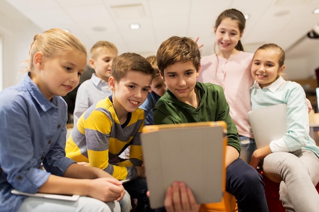 educazione, bambini, tecnologia e concetto di persone - gruppo di bambini felici con computer tablet pc che imparano a scuola