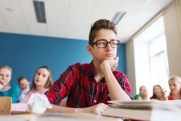 educazione, bullismo, relazioni sociali e concetto di persone - compagni di classe che spettegolano dietro il ragazzo studente a scuola