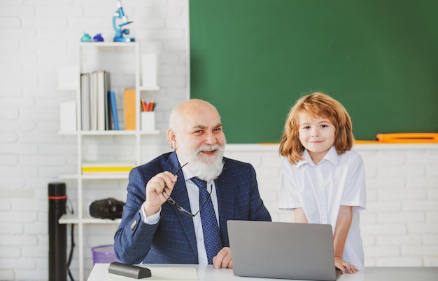 Educazione e apprendimento. Allievo e insegnante con laptop. L'insegnante aiuta a imparare. Buone lezioni. Di nuovo a scuola. Insegnante con scolaro in classe.