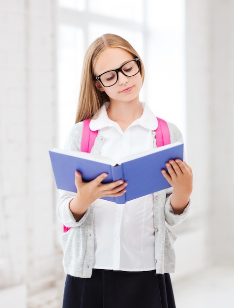 educazione e concetto di scuola - piccola studentessa che legge un libro a scuola