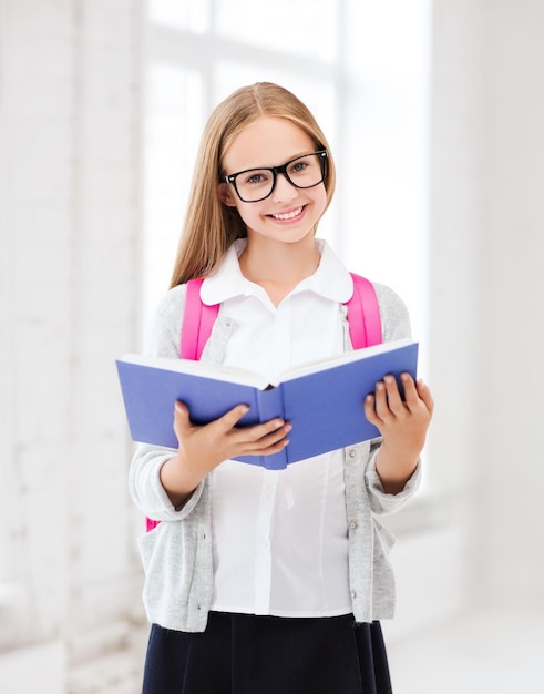 educazione e concetto di scuola - piccola studentessa che legge un libro a scuola