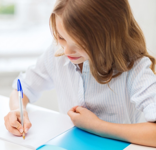 educazione e concetto di scuola - piccola studentessa che scrive sul taccuino a scuola