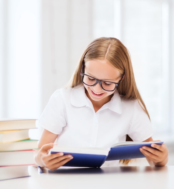 educazione e concetto di scuola - piccola studentessa che studia e legge libri a scuola