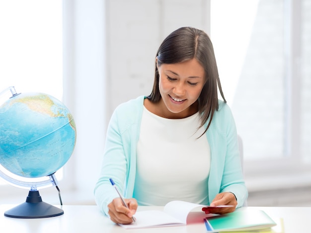 educazione e scuola, concetto di viaggio - insegnante donna con globo e blocco note