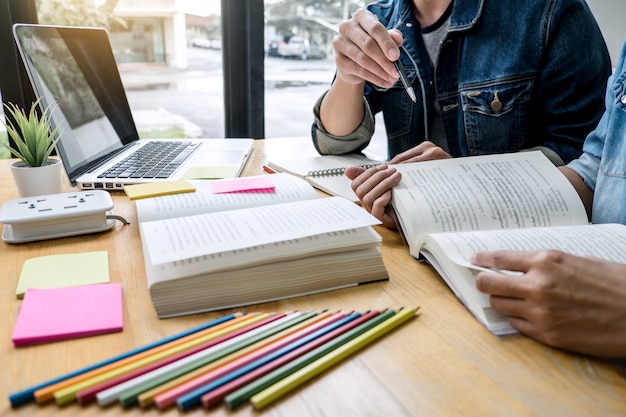 Educazione, insegnamento, apprendimento, tecnologia e concetto di persone. Due studenti delle scuole superiori o compagni di classe con l&#39;aiuto di un amico fanno i compiti a casa in classe, i libri del tutor con gli amici