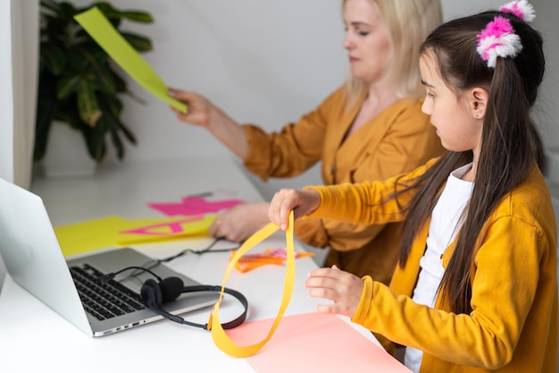 Educazione online dei bambini. Madre e figlia di scuola materna che guardano una lezione video chiamata chat corso creativo disegno artistico usando lapott a casa.