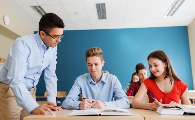 educazione, scuola, apprendimento, insegnamento e concetto di persone - gruppo di studenti e insegnanti che parlano in classe