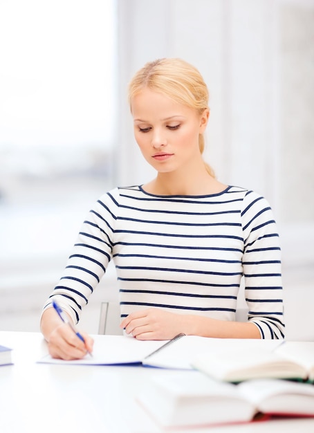 educazione, scuola e concetto di business - donna concentrata con libri e taccuino che studiano all'università