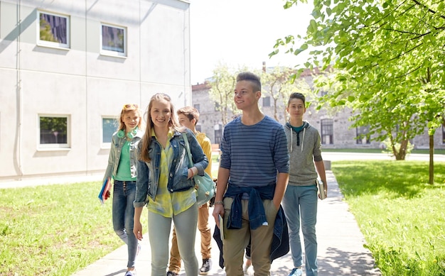 educazione, scuola superiore, comunicazione e concetto di persone - gruppo di studenti adolescenti felici che camminano all'aperto