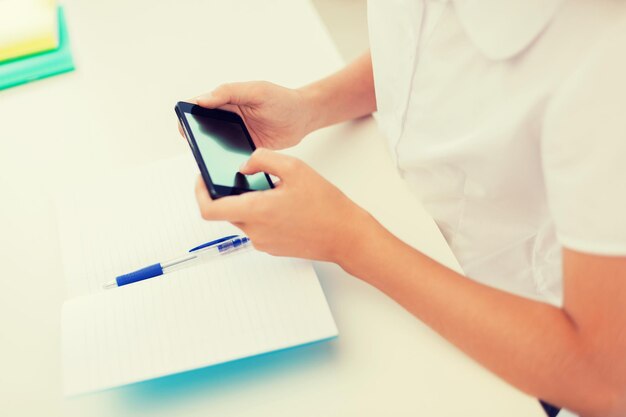 educazione, scuola, tecnologia e concetto di internet - piccola studentessa con quaderni e smartphone a scuola