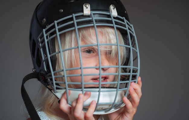 Educazione sportiva e carriera Ragazza carina bambino indossare casco da hockey primo piano Sicurezza e protezione Griglia protettiva sul viso Attrezzatura sportiva Casco da hockey o rugby Sport infanzia Futura stella dello sport