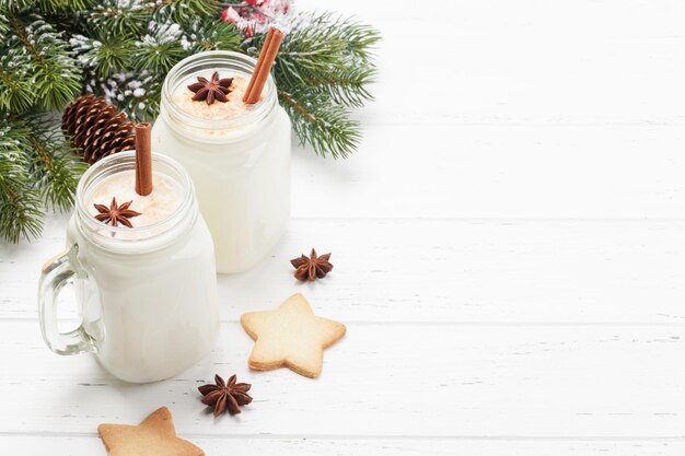 Eggnog tradizionale cocktail di Natale e biscotti di pan di zenzero su tavolo di legno con spazio per le copie per i tuoi auguri di Natale