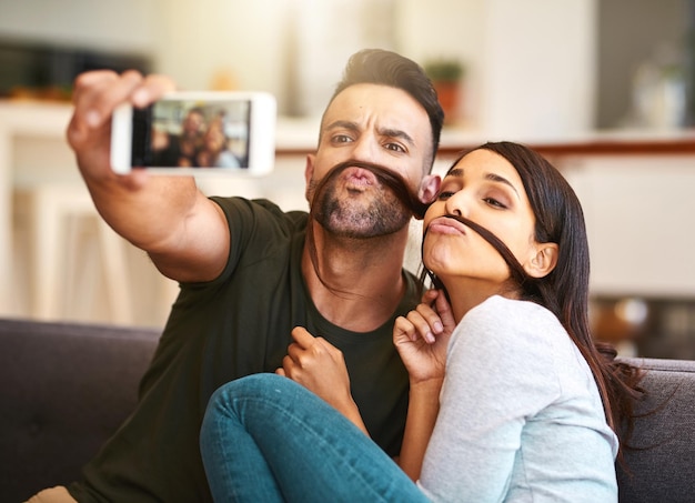 Ehi mondo, cosa ne pensi dei nostri staches Foto di una giovane coppia che si fa selfie insieme a casa