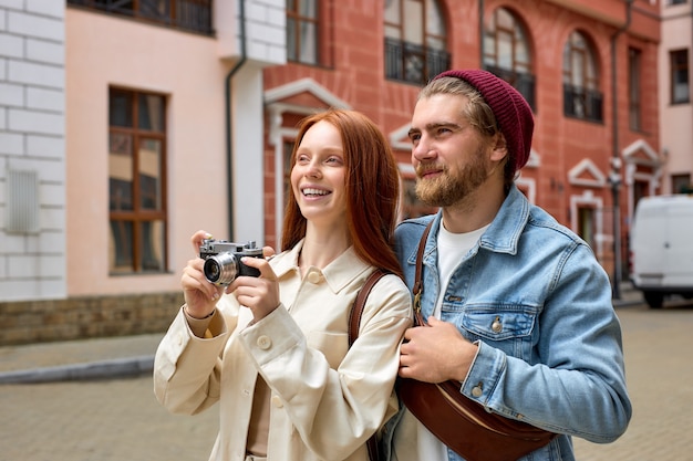 Elaborare o scattare foto del centro storico da parte di fotografi viaggiatori. Coppia viaggia insieme. Ritratto di vista laterale di un bell'uomo e di una donna caucasici in abbigliamento casual che si godono il viaggio nella nuova città