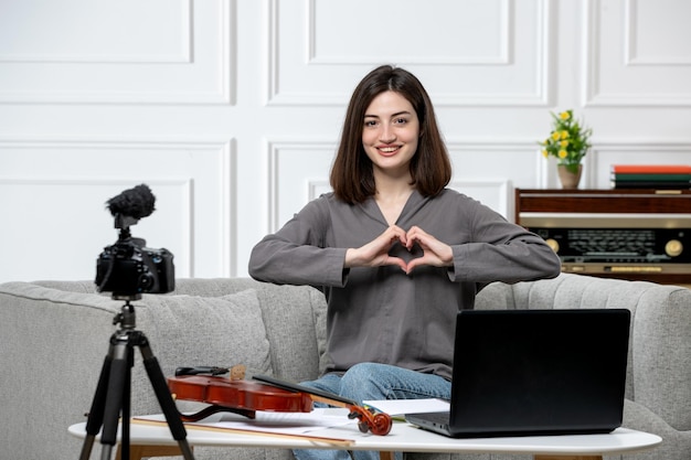 Elearning giovane bella ragazza carina a distanza a casa dando lezioni di violino inviando amore