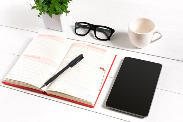 Elegante ambiente di lavoro minimalista con tablet e notebook e occhiali in stile piatto. Sfondo bianco. Vista dall'alto. Copia spazio