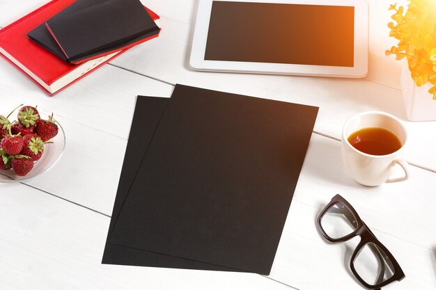 Elegante ambiente di lavoro minimalista con tablet e notebook e occhiali in stile piatto sfondo bianco