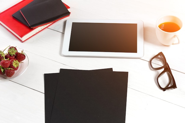 Elegante ambiente di lavoro minimalista con tablet e notebook e occhiali in stile piatto sfondo bianco