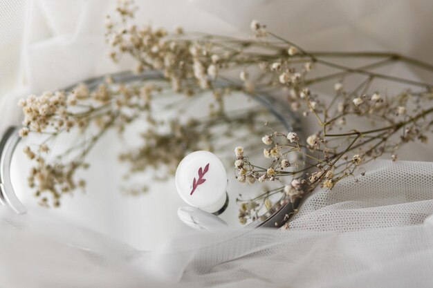 Elegante anello rotondo bianco moderno e fiori secchi sullo specchio su morbido spazio di copia in tulle bianco